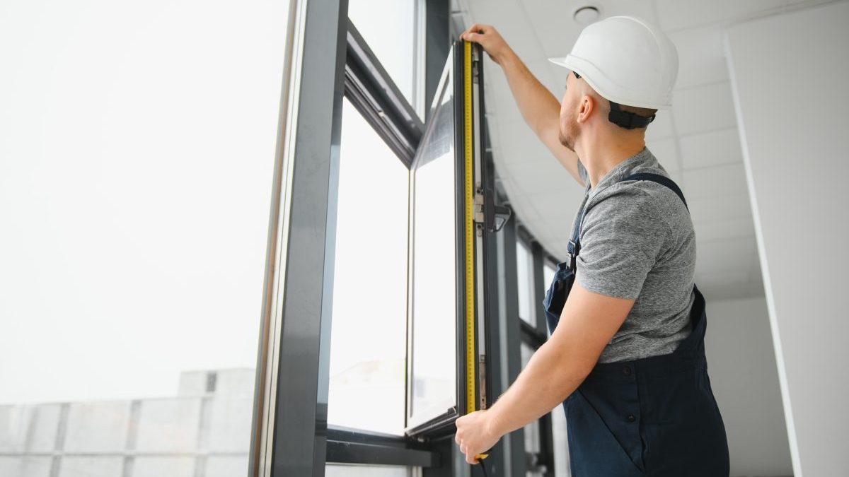 Construction worker repairing plastic window with screwdriver indoors, space for text. Banner design